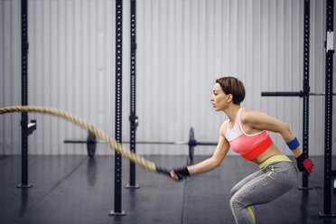 Selbstbewusste Sportlerin, die im Fitnessstudio mit einem Seil trainiert - CAVF45478