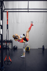 Seitenansicht einer Sportlerin, die ihren Freund beim Training im Fitnessstudio trägt - CAVF45486
