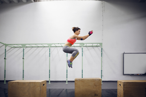 Seitenansicht eines selbstbewussten weiblichen Athleten beim Boxsackspringen im Fitnessstudio, lizenzfreies Stockfoto
