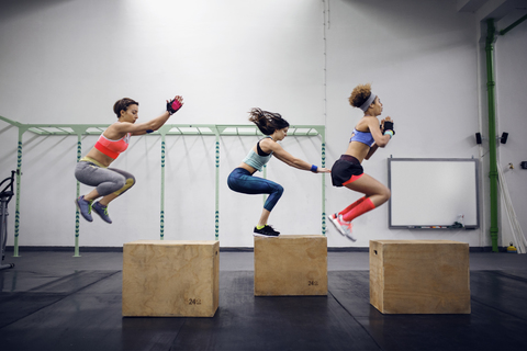 Seitenansicht von entschlossenen weiblichen Athleten beim Boxspringen im Fitnessstudio, lizenzfreies Stockfoto