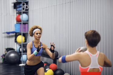 Entschlossene Sportlerinnen beim Training mit einem Medizinball im Fitnessstudio - CAVF45503