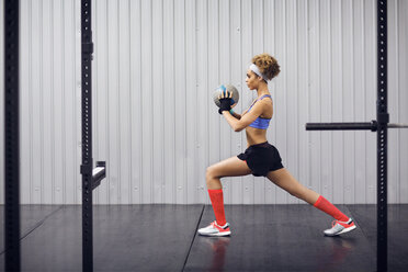 Entschlossene Sportlerin beim Training mit einem Medizinball im Fitnessstudio - CAVF45505