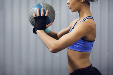 Mittelteil einer Sportlerin beim Training mit einem Medizinball im Fitnessstudio - CAVF45506