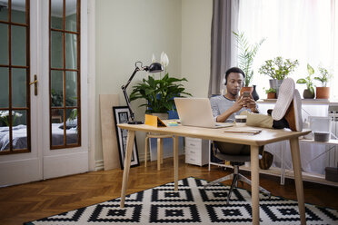 Relaxed man using smart phone at home office - CAVF45533