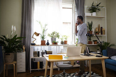 Side view of man using smart phone at home office - CAVF45535