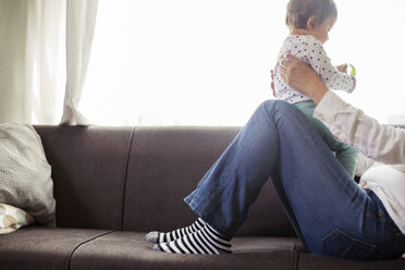 Tiefschnitt einer Frau, die mit ihrer Enkelin auf einem Sofa am Fenster sitzt - CAVF45563