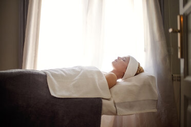 Side view of relaxed woman lying on massage table in spa - CAVF45572