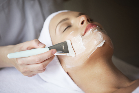 Female therapist applying facial mask on woman's face in spa stock photo