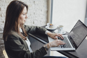 Side view of businesswoman using laptop in restaurant - CAVF45612