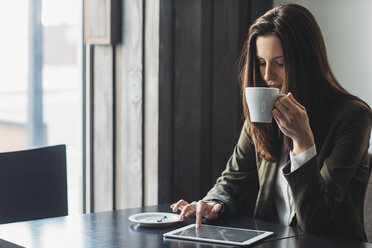 Geschäftsfrau trinkt Kaffee, während sie einen Tablet-Computer am Cafétisch benutzt - CAVF45617