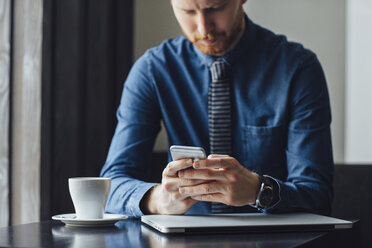 Businessman using smart phone while sitting at restaurant table - CAVF45625