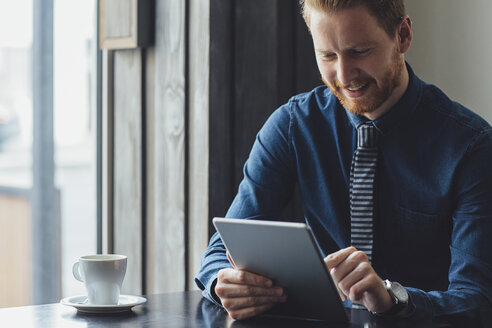 Glücklicher Geschäftsmann mit Tablet-Computer am Restauranttisch - CAVF45627