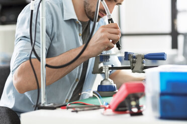 Engineer using drill on circuit board in electronic laboratory - CAVF45676