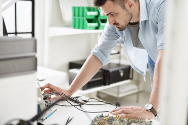 Ingenieur bei der Arbeit mit Leiterplatten am Tisch im Elektroniklabor - CAVF45685