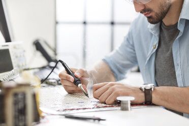 Ausgeschnittenes Bild eines Ingenieurs beim Löten einer Leiterplatte in einem Elektroniklabor - CAVF45689