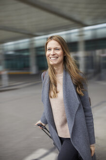 Porträt einer selbstbewussten Geschäftsfrau, die auf dem Flughafen einen Koffer zieht - PNEF00603