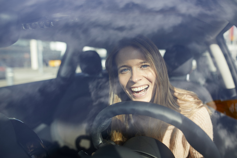 Porträt einer lachenden jungen Frau im Auto, lizenzfreies Stockfoto
