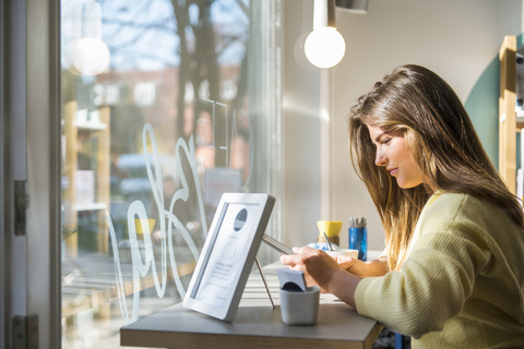 Junge Frau benutzt Tablet in einem Café, lizenzfreies Stockfoto