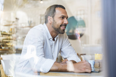 Smiling man with tablet in a cafe - DIGF03925