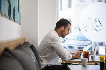 Man using tablet in a cafe - DIGF03932