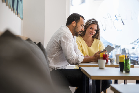Young woman and man sharing tablet in a cafe stock photo