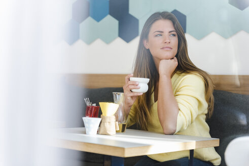 Junge Frau in einem Cafe mit einer Tasse Kaffee in der Hand - DIGF03936