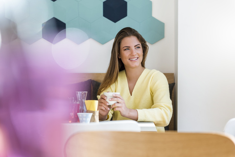 Smiling young woman in a cafe holding cup of coffee stock photo