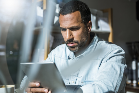 Mann benutzt Tablet in einem Café, lizenzfreies Stockfoto