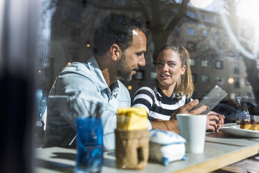Junge Frau und Mann teilen sich ein Tablet in einem Cafe - DIGF03944
