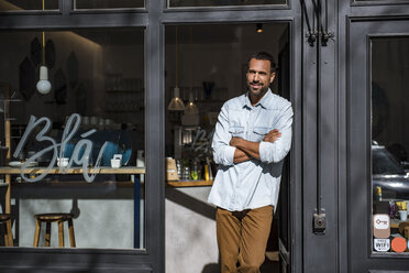 Lächelnder Mann vor der Eingangstür eines Cafés - DIGF03948