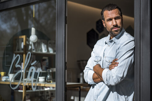 Mann an der Eingangstür eines Cafés schaut sich um - DIGF03949