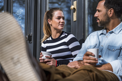 Man and woman sitting outside a cafe talking stock photo
