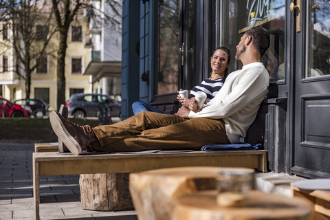 Mann und Frau sitzen vor einem Cafe und unterhalten sich, lizenzfreies Stockfoto