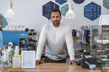Portrait of confident owner behind the counter of a cafe - DIGF03960