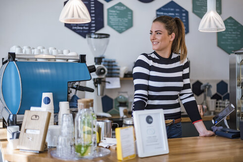 Lächelnde junge Frau hinter dem Tresen eines Cafés - DIGF03962