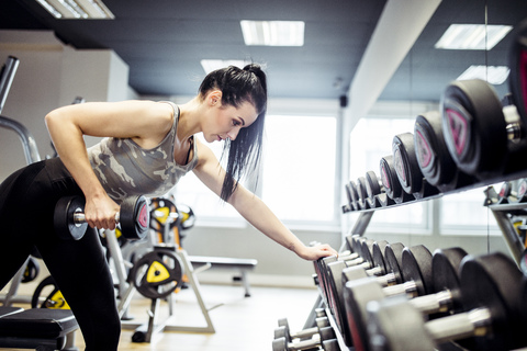 Frau beim Training mit Hanteln im Fitnessstudio, lizenzfreies Stockfoto