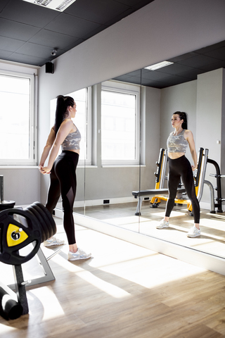 Frau trainiert im Fitnessstudio und schaut in den Spiegel, lizenzfreies Stockfoto
