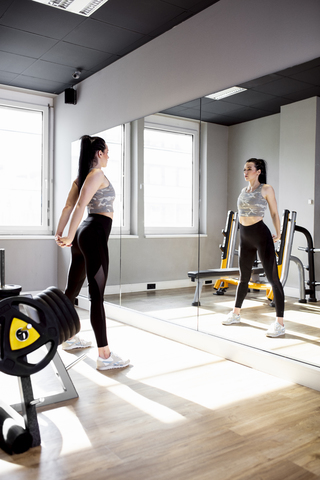 Woman exercising in gym looking in mirror stock photo