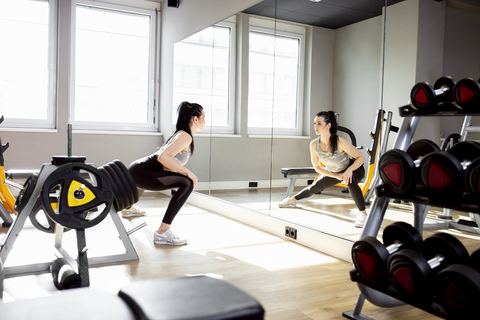 Frau trainiert im Fitnessstudio und schaut in den Spiegel, lizenzfreies Stockfoto