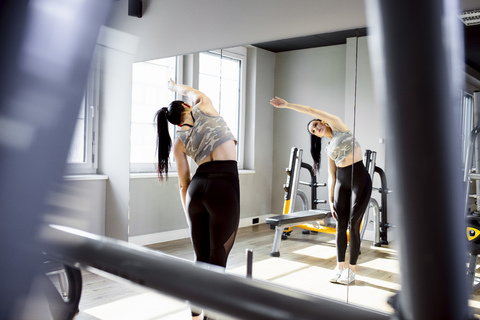 Frau trainiert im Fitnessstudio und schaut in den Spiegel, lizenzfreies Stockfoto