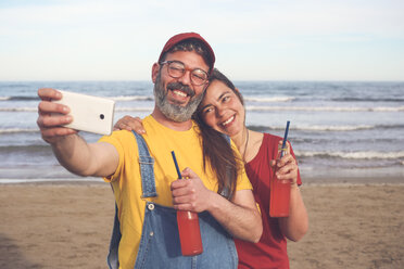 Paar mit alkoholfreien Getränken macht Selfie mit Smartphone am Strand - RTBF01176