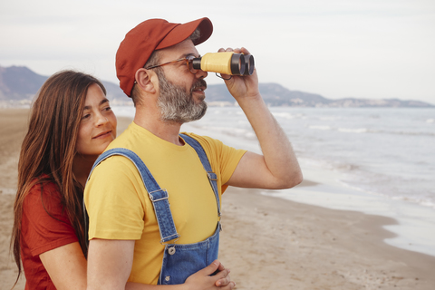 Pärchen mit Fernglas am Strand, lizenzfreies Stockfoto