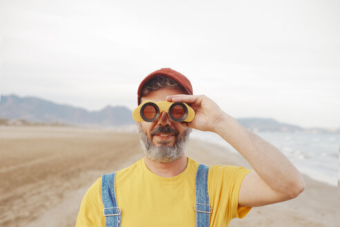 Bearded man using binoculars on the beach - RTBF01182