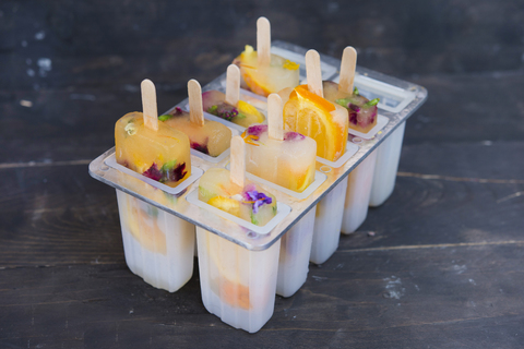 Homemade orange and lemon popsicles with edible flowers stock photo
