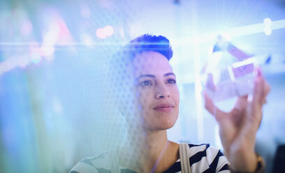 Innovative female entrepreneur examining glass cube prototype - HOXF03361