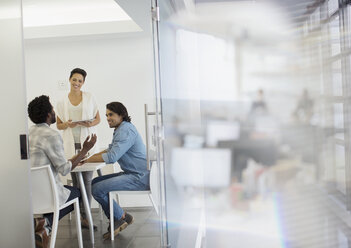 Smiling business people talking in conference room meeting - HOXF03398