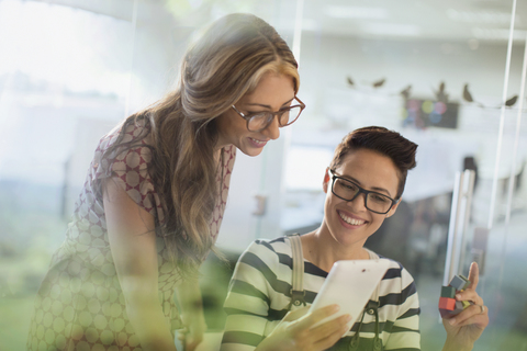 Lächelnde, kreative Geschäftsfrauen mit Prototyp und digitalem Tablet, lizenzfreies Stockfoto