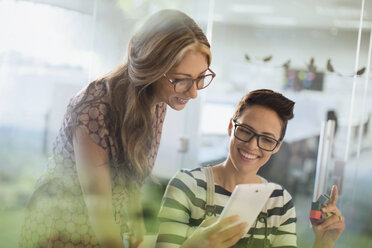 Smiling creative businesswomen with prototype using digital tablet - HOXF03401