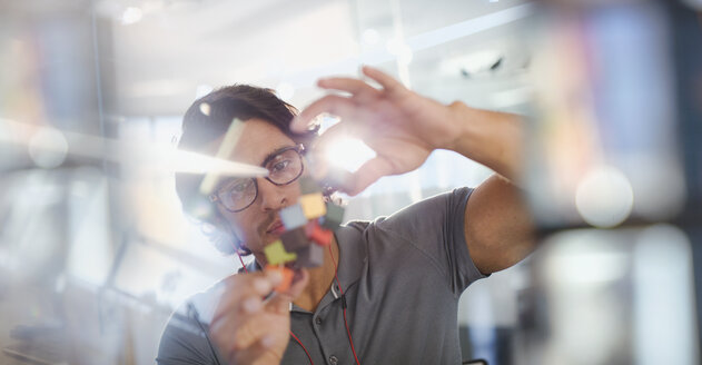 Focused, innovative male entrepreneur examining prototype - HOXF03414