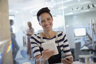 Porträt einer lächelnden, selbstbewussten, kreativen Geschäftsfrau, die ein digitales Tablet im Büro benutzt - HOXF03432